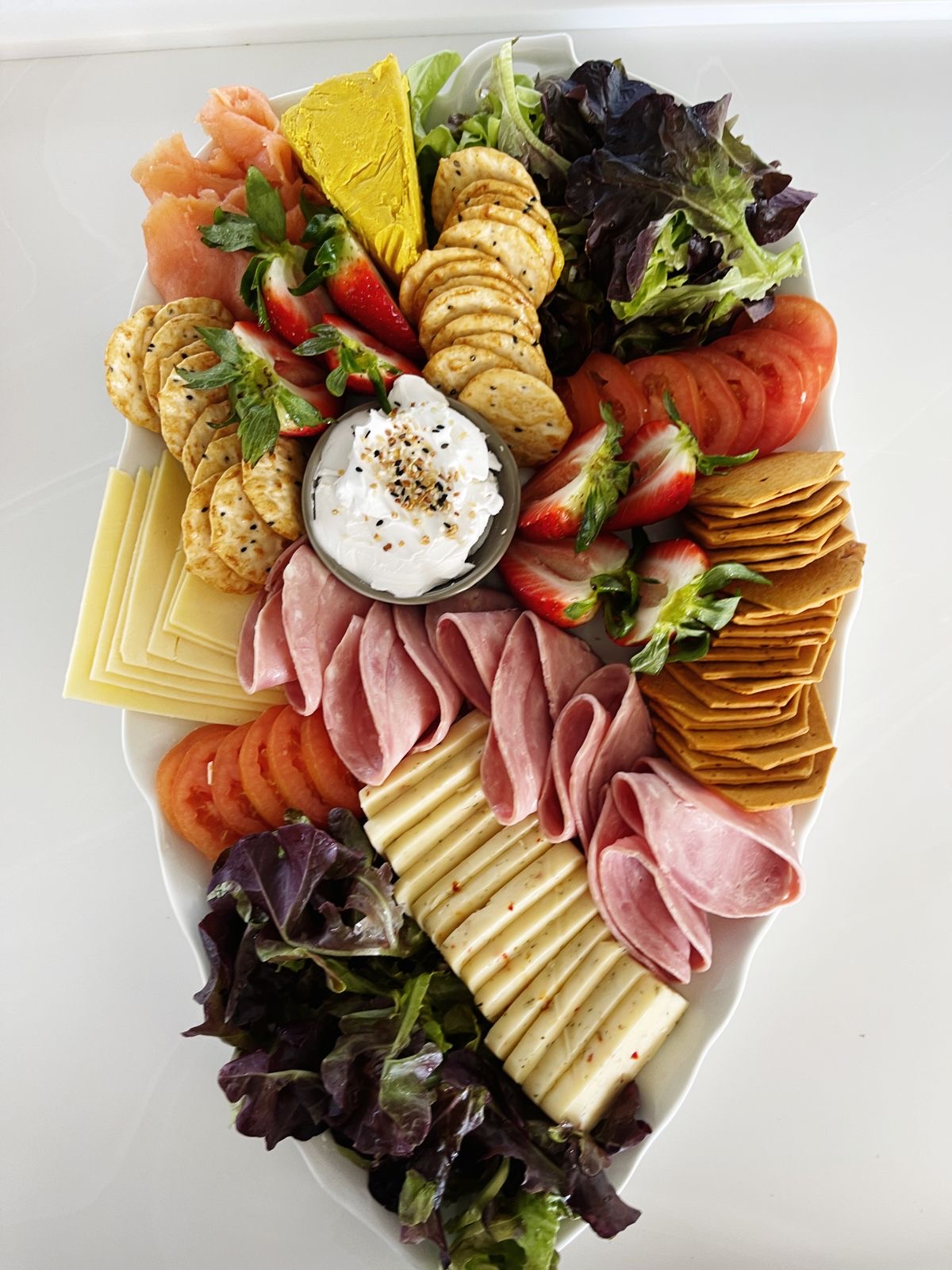 Platter of cured meats, cheese, crackers and strawberries
