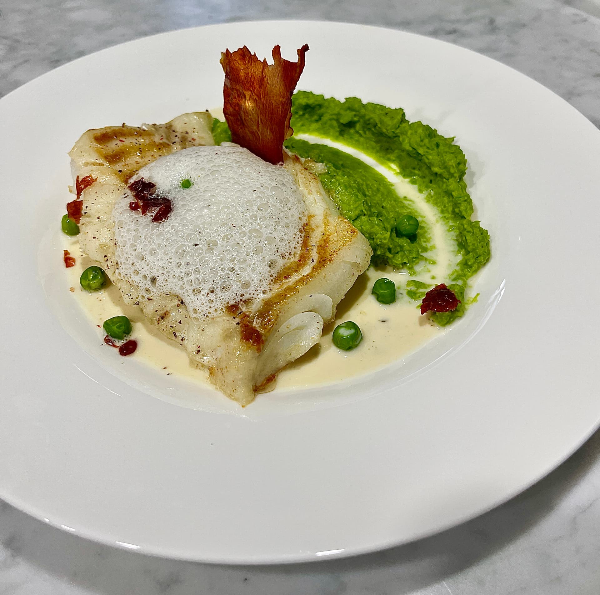 Seared fish plated with culinary foam and pea purée