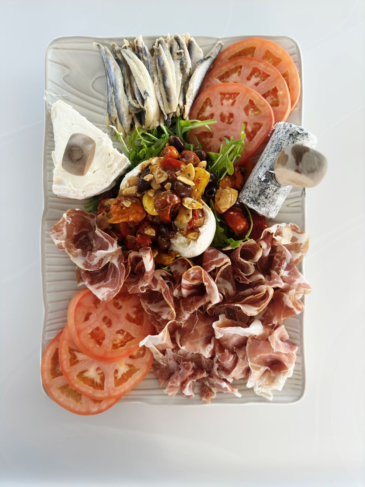 Mediterranean board with cured meats, cheese and tomatoes
